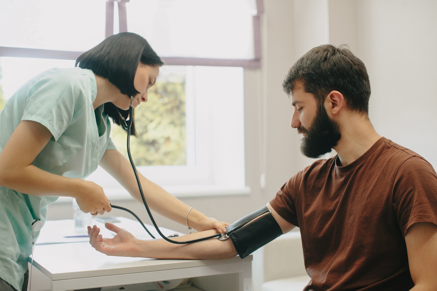 Nurse checking man’s blood pressure in clinic