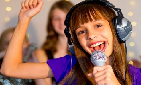 Group of happy girls singing on karaoke