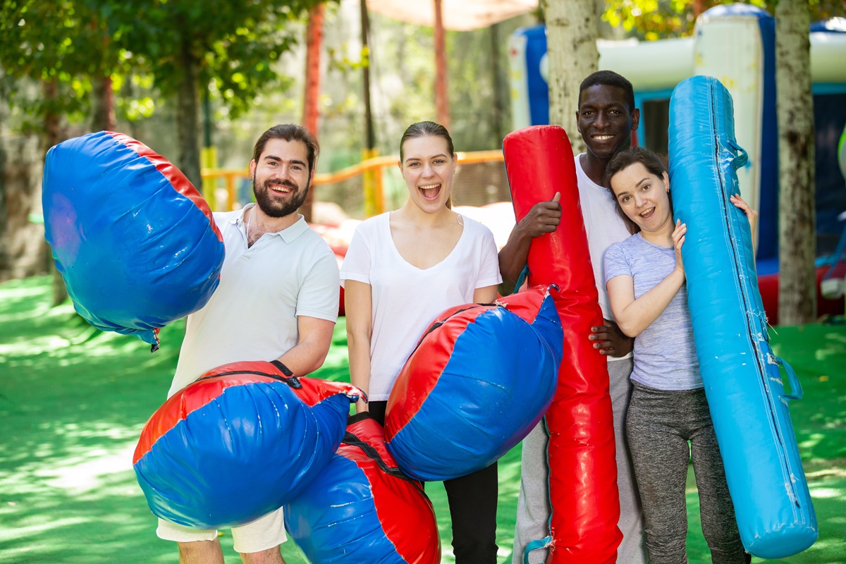 Portrait of happy friends with inflatable logs and pillows at an amusement park